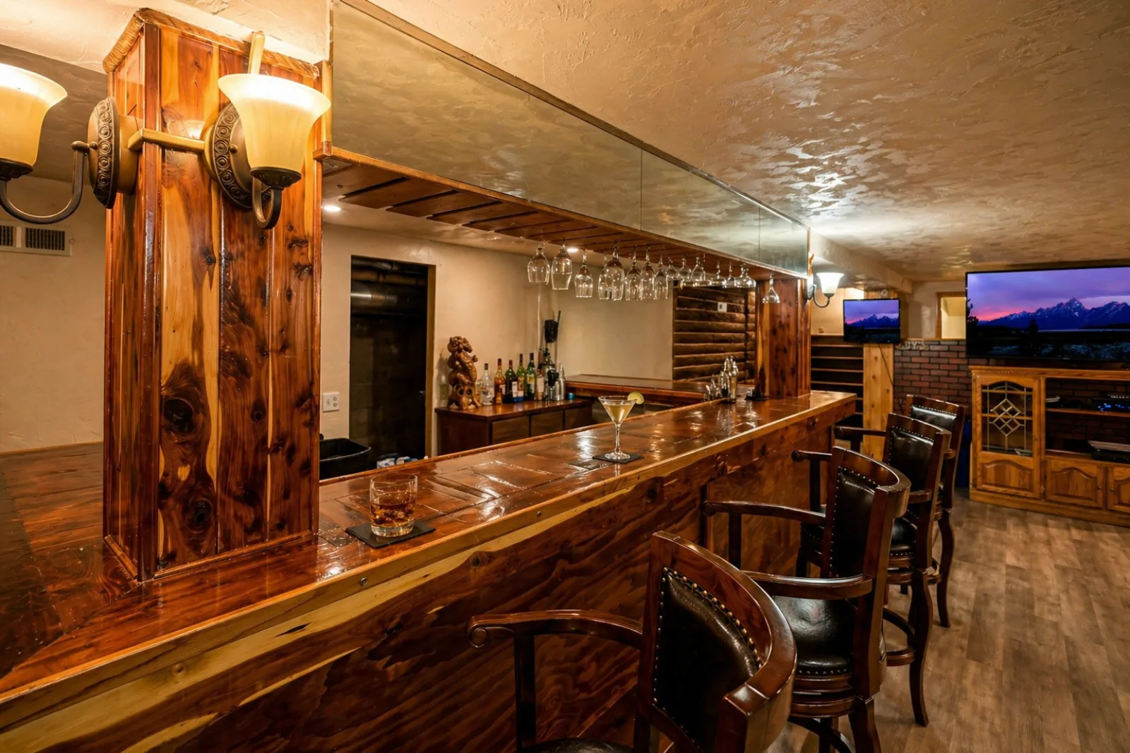 The cedar bar at Harbour Hideout — backbar mirror, hanging stemware, and leather stools in downtown Sheridan, Wyoming.